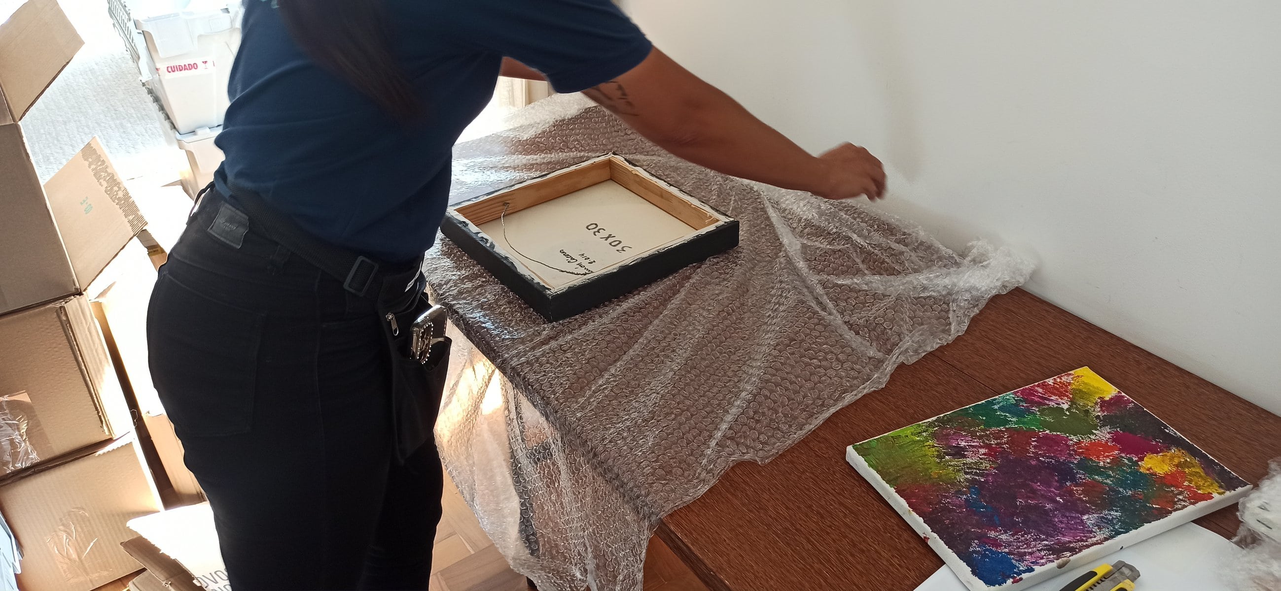 Profissional da Osmar embalando um quadro em plástico-bolha