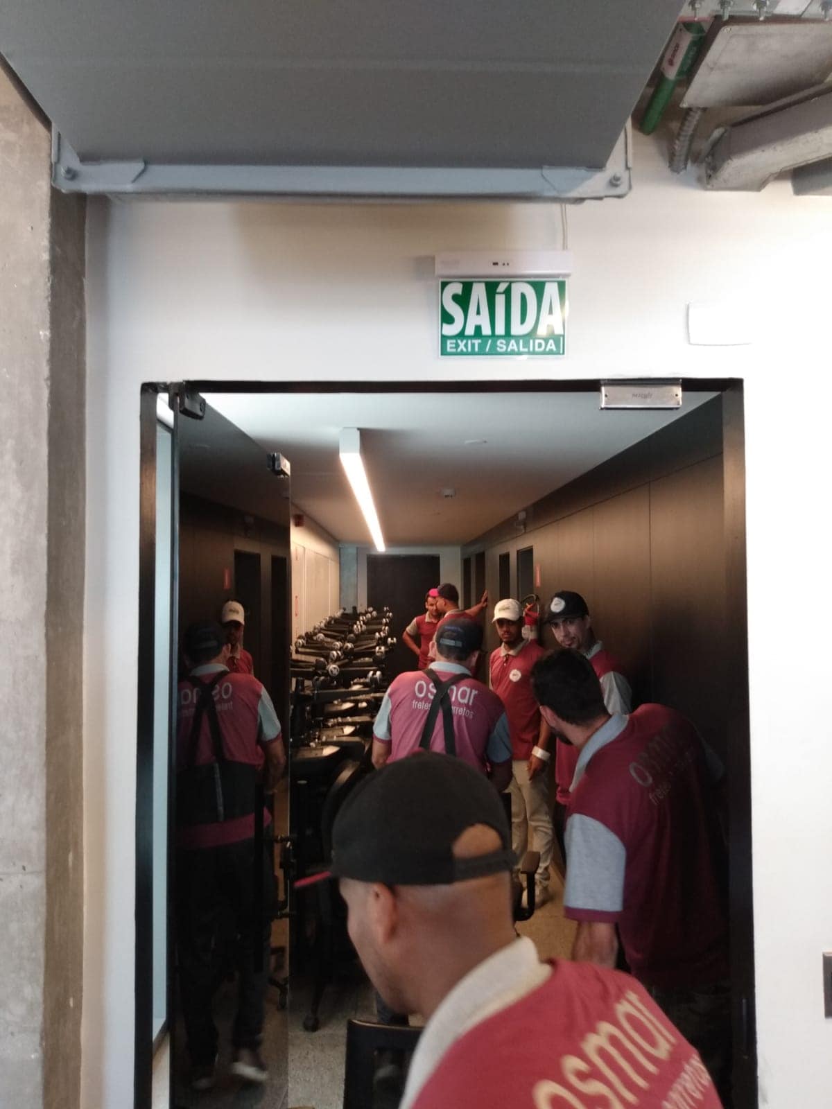 Equipe da Osmar transportando cadeiras de escritório pelo corredor do prédio