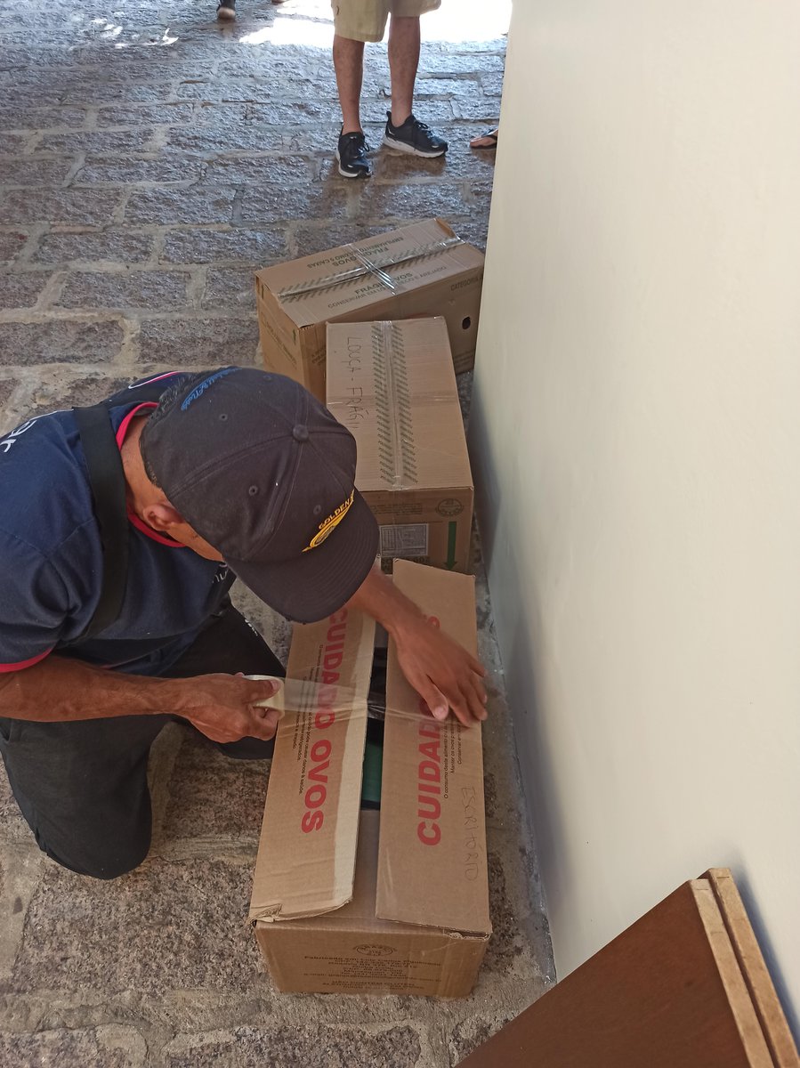 ajudante fechando caixa com fita adesiva