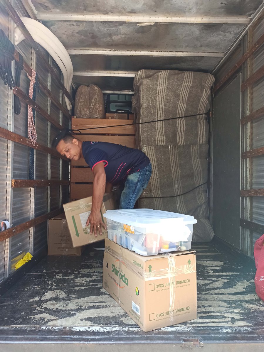 ajudante amarrando carga de móveis no caminhão
