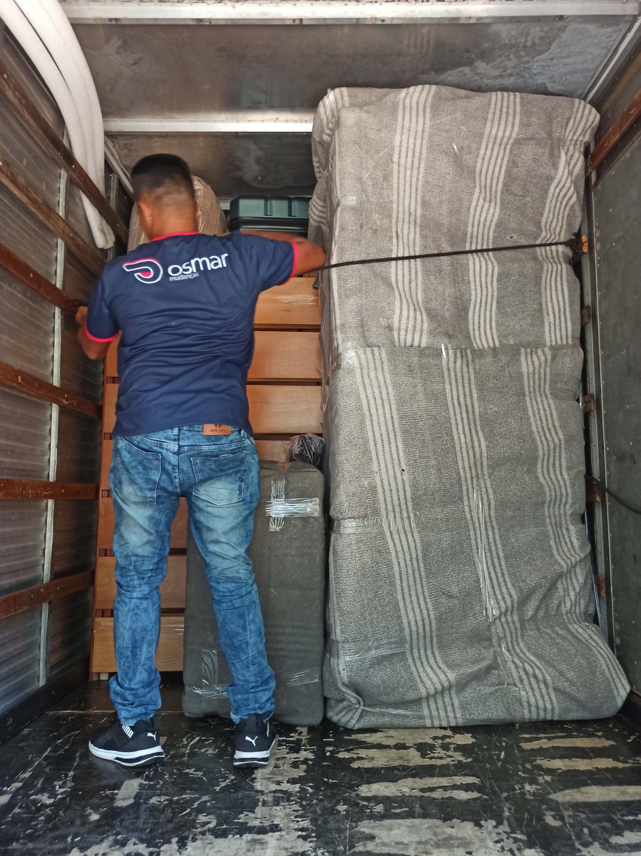 ajudante amarrando carga de móveis no caminhão