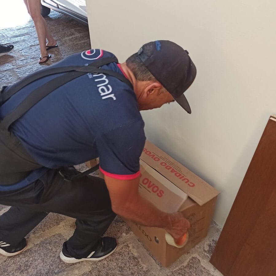 ajudante fechando caixa com fita adesiva