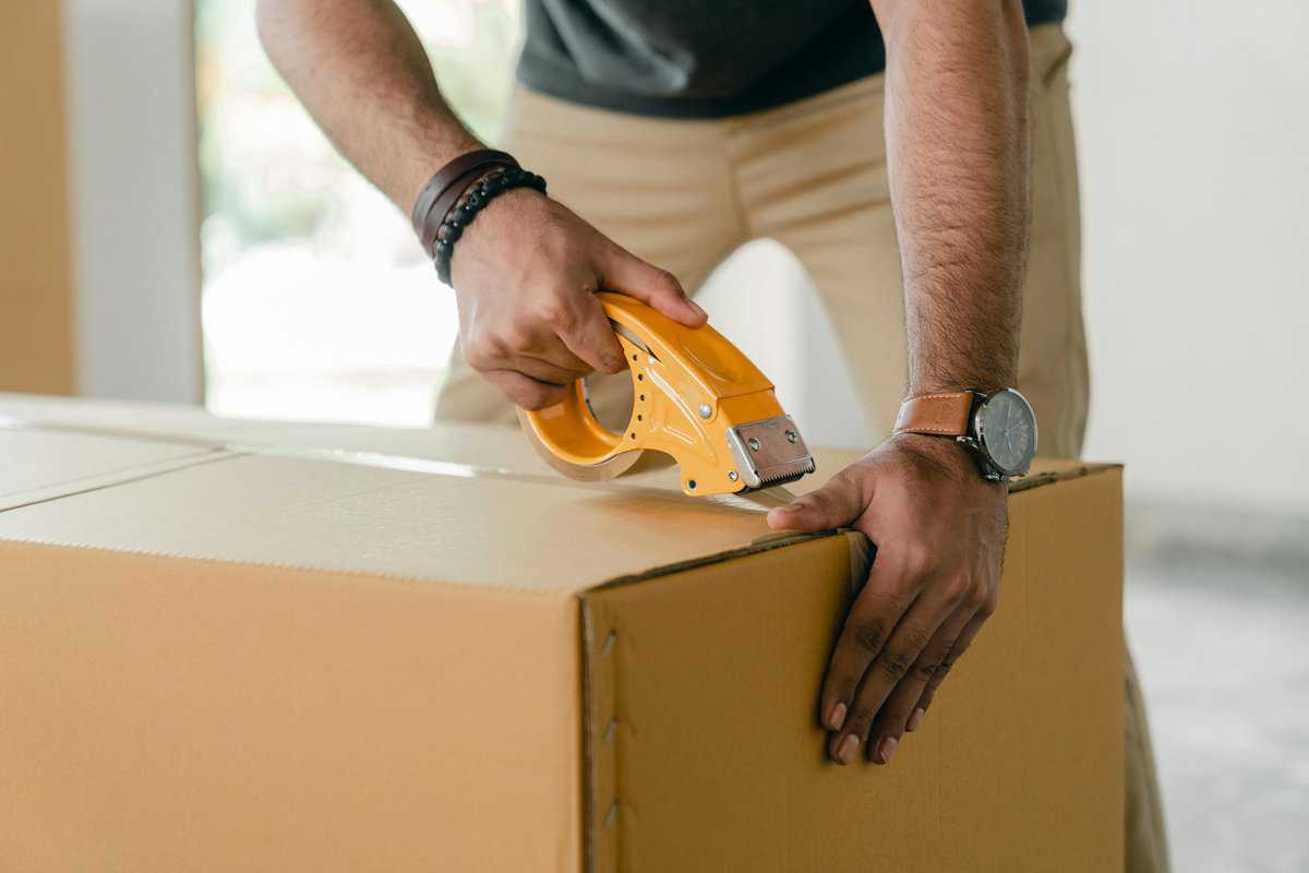 man sealing box with tape